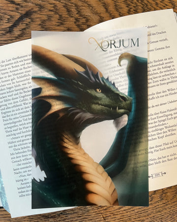 Das Page Overlay zeigt das Profil eines grünen Drachen. Das Page Overlay liegt auf einem aufgeschlagenen Buch, so dass man die Buchstaben durch das Papier schimmern sieht.